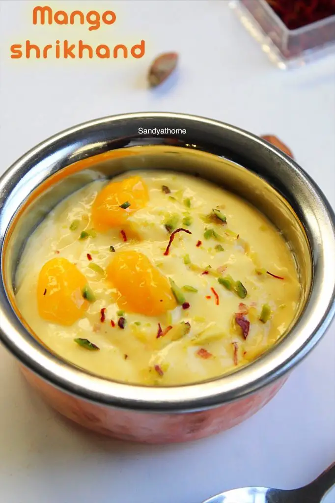 Chilled mango shrikhand with saffron strands and cardamom in a rustic bowl
