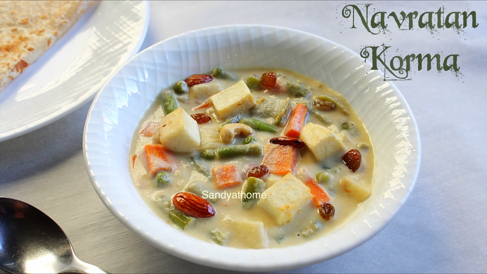Creamy Navratan Korma curry with nine colorful ingredients like paneer, carrots, peas, cashews, and saffron, served in a royal-style brass bowl