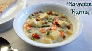 Close-up of restaurant-style Navratan Korma in white gravy with fried cashews, raisins, almonds, and paneer, styled for a festive Indian meal