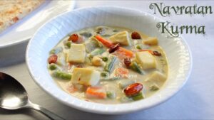 Creamy Navratan Korma curry with nine colorful ingredients like paneer, carrots, peas, cashews, and saffron, served in a royal-style brass bowl
