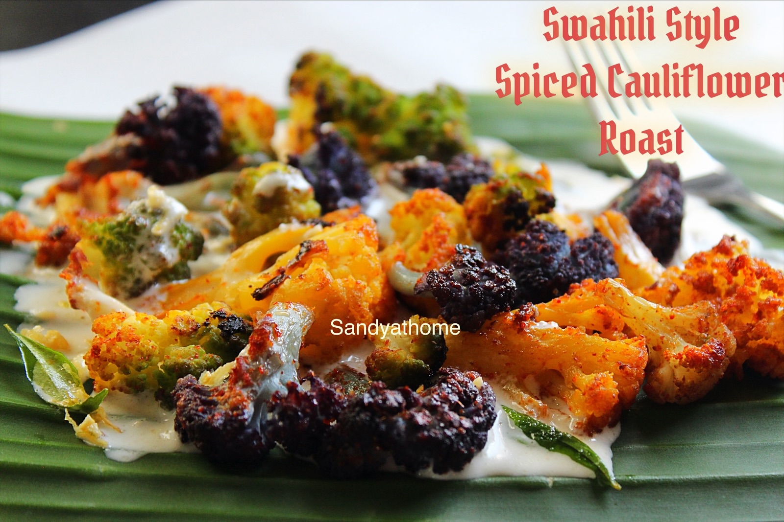 Swahili-inspired Indian fusion dish featuring roasted colorful cauliflower on banana leaf, served with creamy cashew curd white sauce; healthy Trader Joe’s cauliflower recipe with spices like cumin and garlic, plated as a vibrant African Indian appetizer or starter.