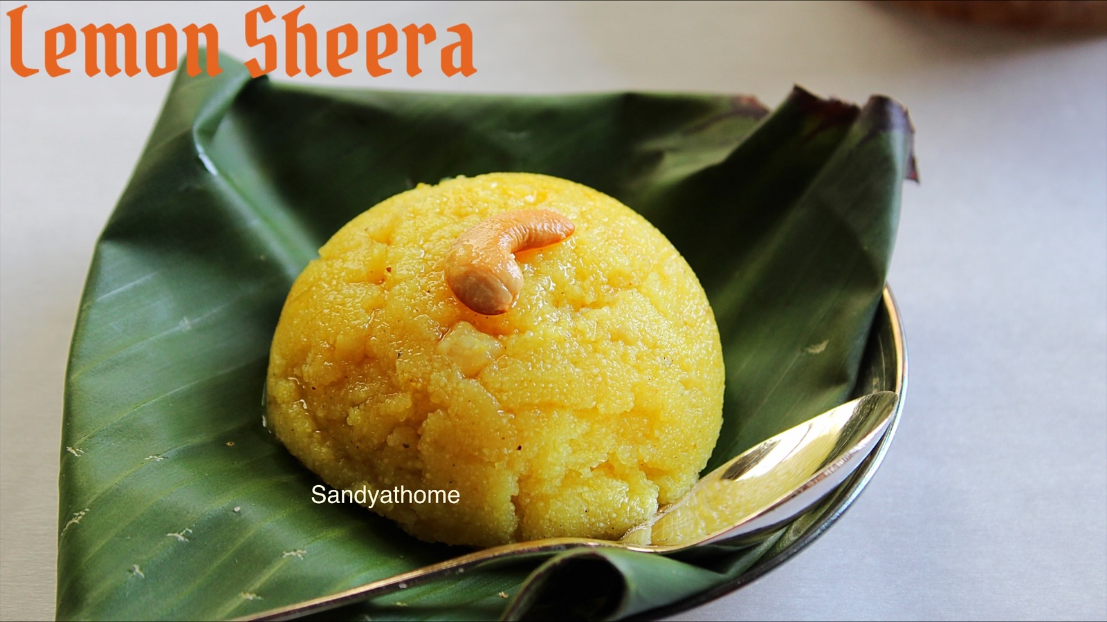 Close-up of lemon kesari served in a brass bowl, topped with candied lemon peel and ghee drizzle