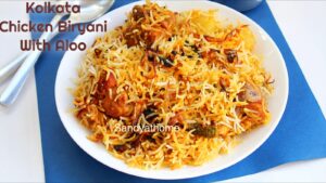 Chicken biryani with basmati rice, fried aloo, and chicken, neatly plated with raita and boiled egg on the side.