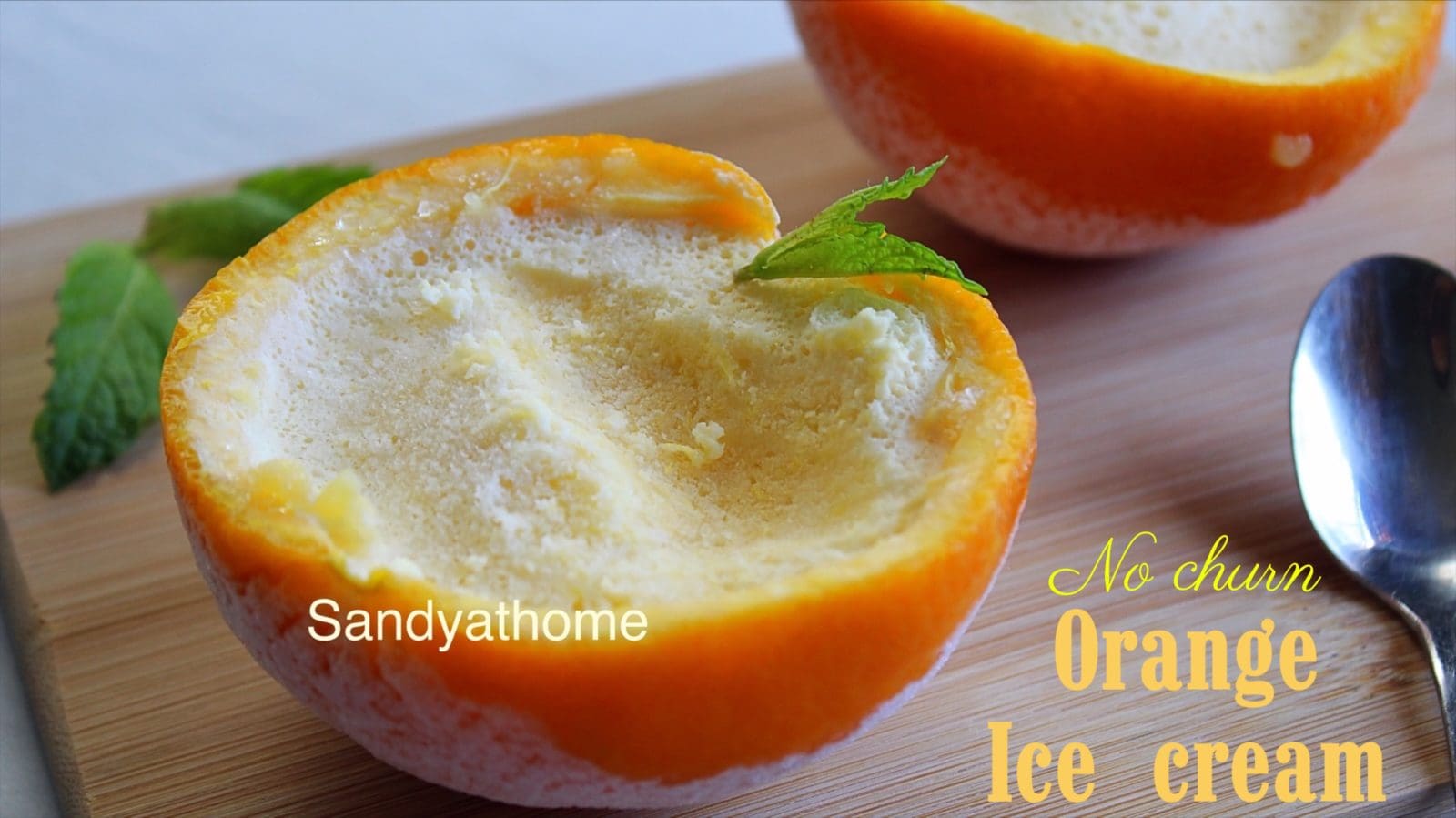 Flat-set orange ice cream in halved citrus shell, rustic no-churn dessert with mint leaf on top