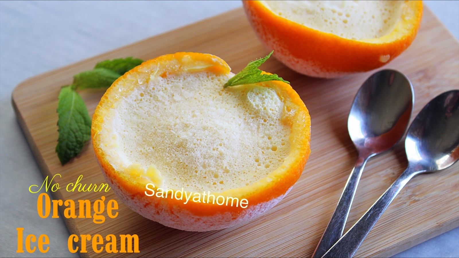 Scoopless orange ice cream made without molds or machines, set inside orange halves, topped with mint