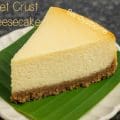 Close-up of a homemade ricotta mascarpone cheesecake slice with ragi jowar wheat biscuit base, lightly scooped with a spoon, styled on a banana leaf for a rustic Indian-inspired dessert presentation.