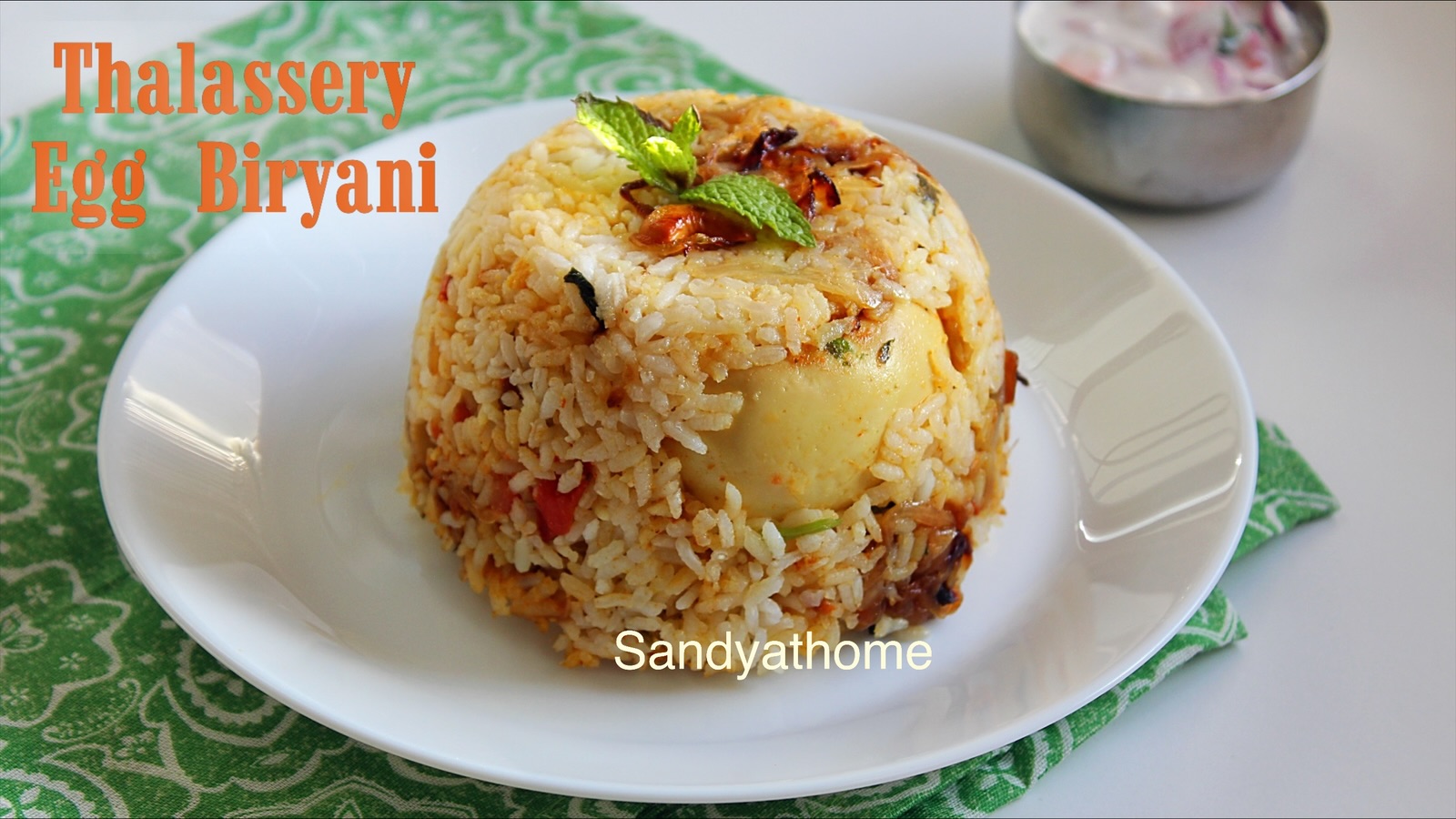 Dum cooked Thalassery egg biryani topped with tawa fried onions, mint, and coriander for authentic Malabar flavor.