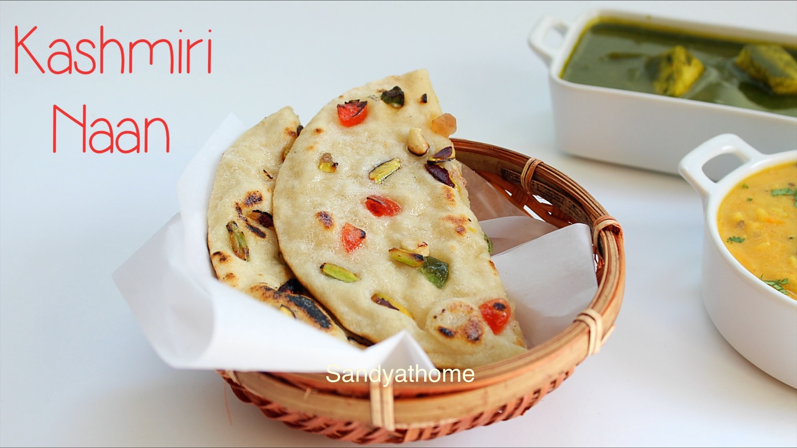 Homemade Kashmiri naan topped with tutti frutti, almonds, and cashews served warm on a plate.