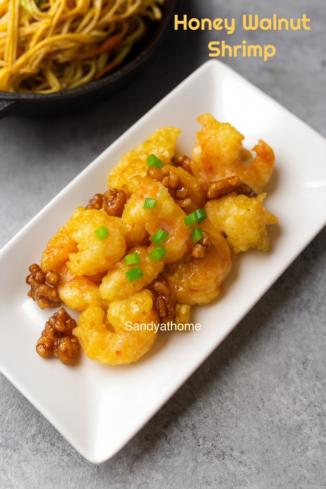 Chinese-American style honey walnut shrimp on a serving platter topped with candied walnuts and a drizzle of honey.